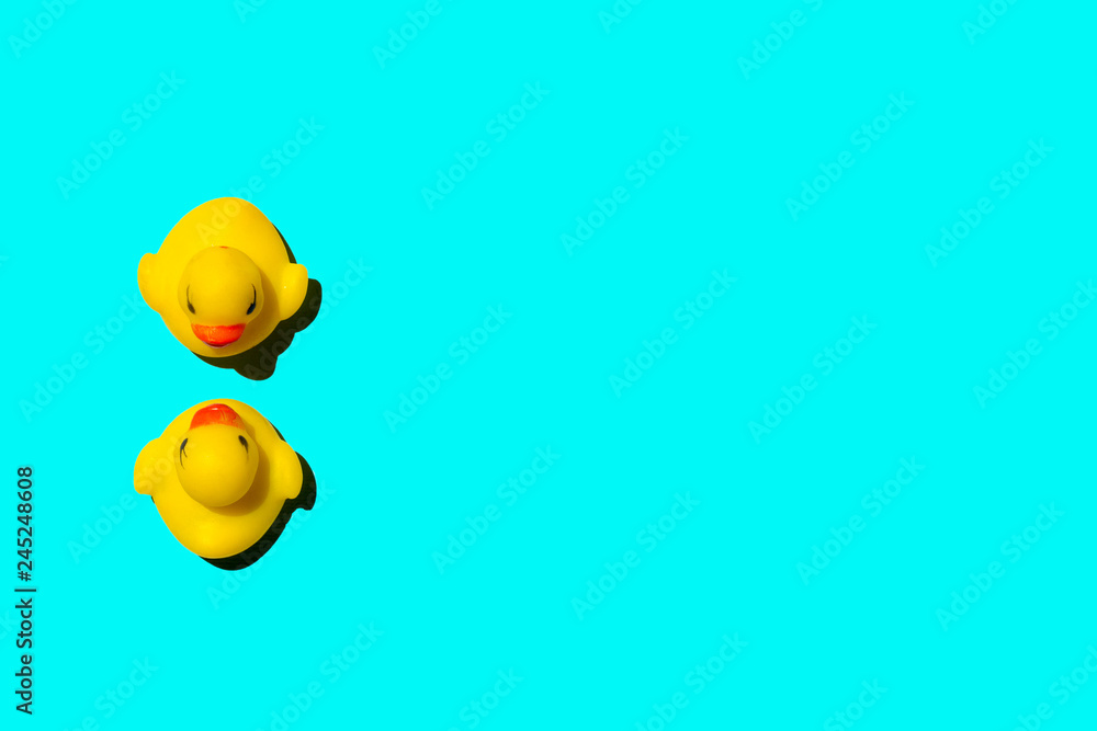 Two rubber ducks on teal background; summer wallpaper with copy space