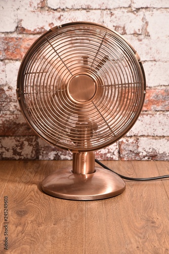 Picture of old style ( brass or copper effect ) electric fan - ventilator with moving blades.