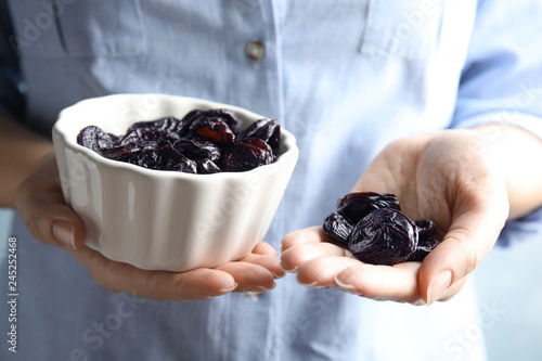 Cuadro en lienzo Woman holding bowl and handful of dried plums, closeup