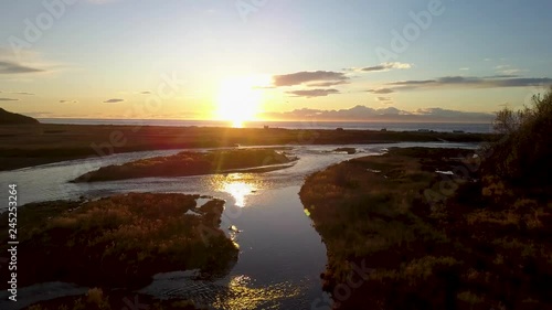 Spectacular aerial drone shot of Cook Inlet flowing in between the grasslands against the golden rays of the setting sun in Deep Creek State Park in Ninilchik, Alaska photo