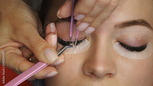 Cosmetic procedure for eyelash extensions in spa salon. Beautician makes correction of volume and length of eyelashes. Shooting close-up.