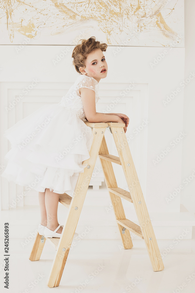 little girl with blond hair wearing white dress.