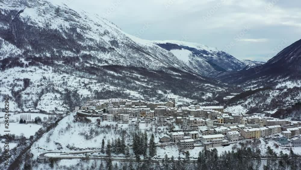 Aerial view of the beautiful snow-covered village of Opi with snow-capped mountains in the background. Opi is a comune and town in the province of L'Aquila in the Abruzzo region of central Italy.. Aerial view of the beautiful snow-covered village of Opi with snow-capped mountains in the background. Opi is a comune and town in the province of L'Aquila in the Abruzzo region of central Italy..