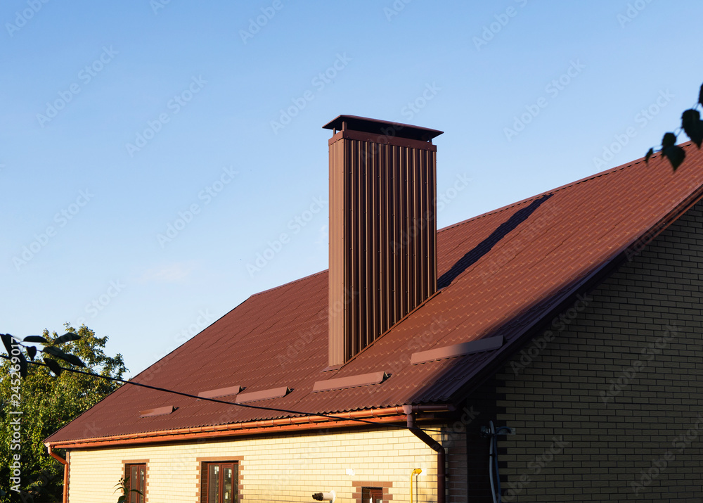 Chimney made of profiled sheeting on the roof with rain gutters and snow guards