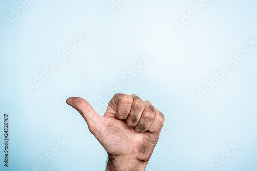 One male dirty hand making thumb up gesture on blue background