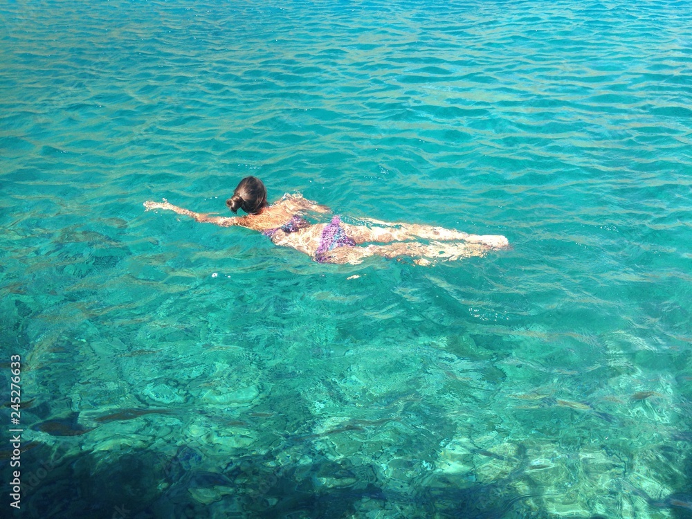 young woman swimming in clear blue water