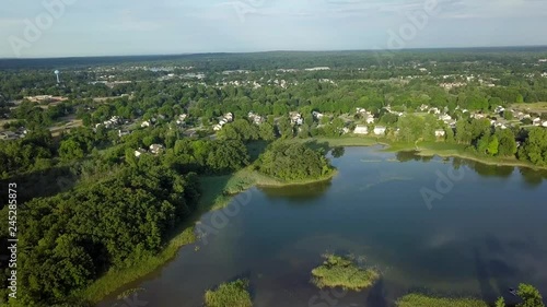 4k Aerial footage of a small lake in the small town of Oxford, Michigan, USA moving towards a suburban residential area in the village of Oxford photo