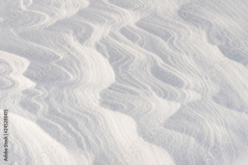 Winding lines from the wind in the snow. Texture of crusty snow. Winter background.