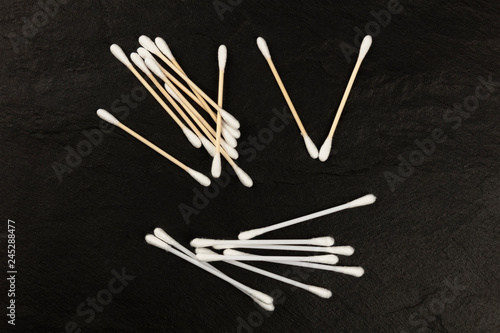 Victory of organic biodegradable bamboo cotton swabs over plastic ones, overhead photo on a black background with a place for text