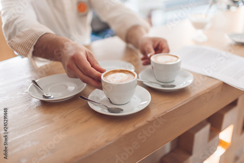 Barista serves two cups of fresh cappuccino in a cafe in the morning