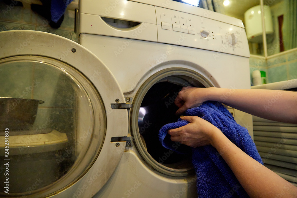 Hands of housewife putting linen into the washing machine in the bath room Hands of housewife putting linen into the washing machine in the bath room