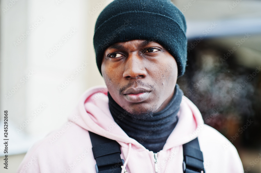 Close up head of stylish urban style african american man in pink hoodie and black hat posed. Frozen breath. Close up head of stylish urban style african american man in pink hoodie and black hat posed. Frozen breath.