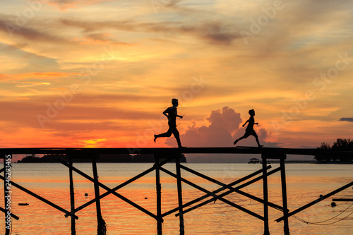 silhouette kids walk on the wooden jetty during sunset at Mantanani Island, Kota Belud, Sabah, Malaysia