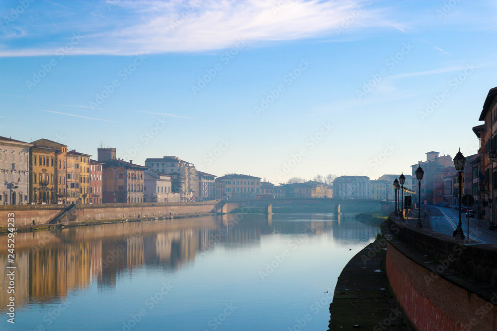 Aerial view of Arno river in Pisa with colorful medieval houses and their reflections at the winter morning fog, Tuscany, Italy