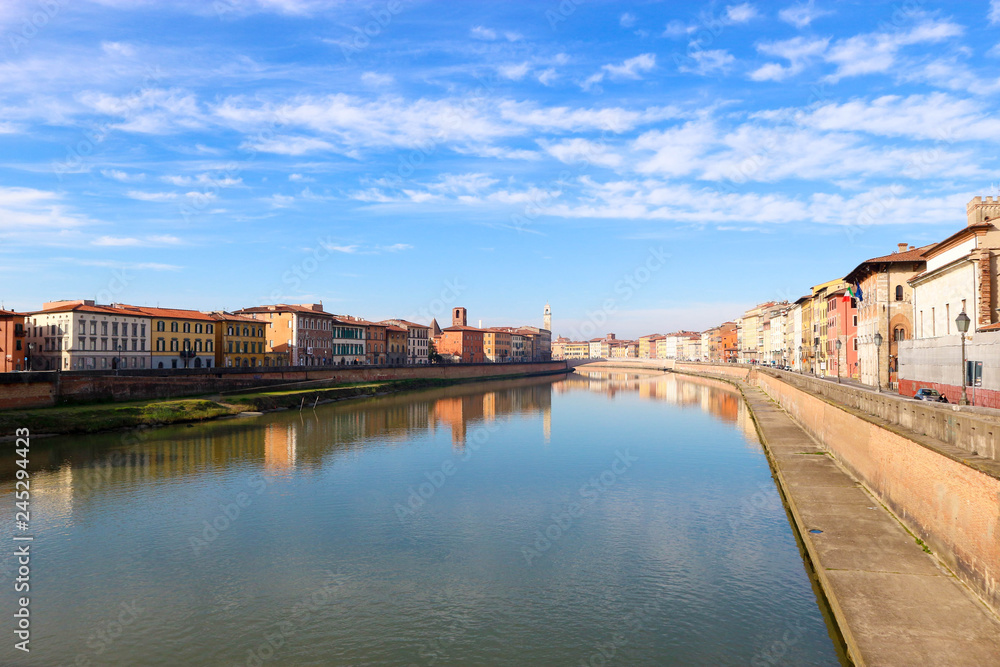 Arno river and colorful houses around under the clear winter sky, Pisa, Tuscany, Italy