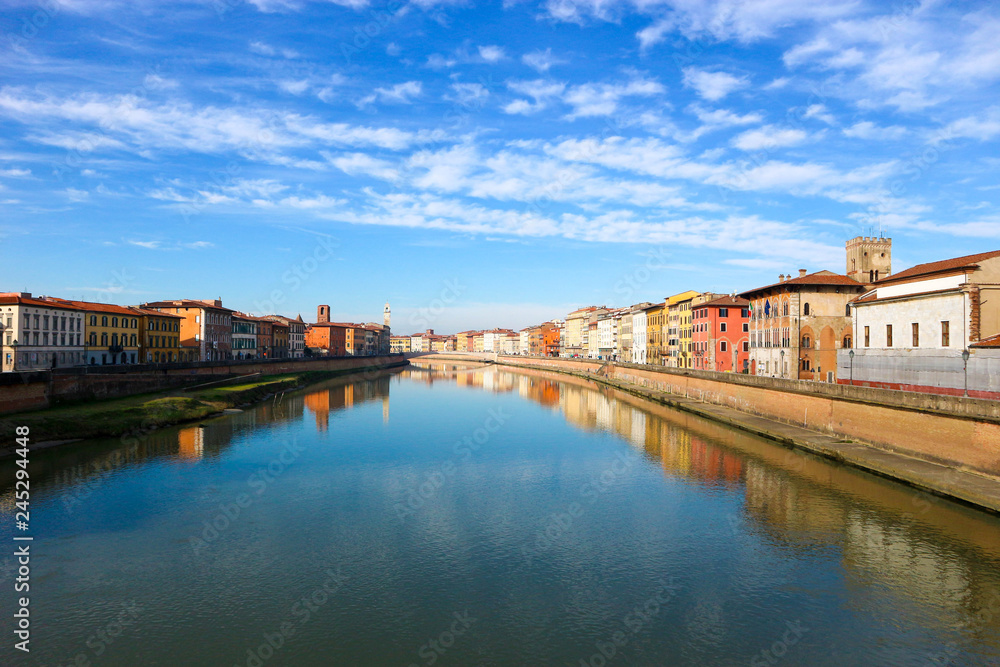 Arno river and colorful houses around under the clear winter sky, Pisa, Tuscany, Italy