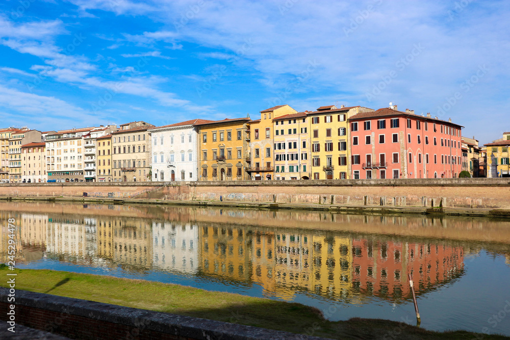 Colorful houses are reflected in the water of arno river under clear sky in Pisa, Tuscany, Italy