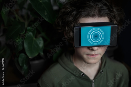 A young boy with a virtual mask with a blue pattern on his face at home.