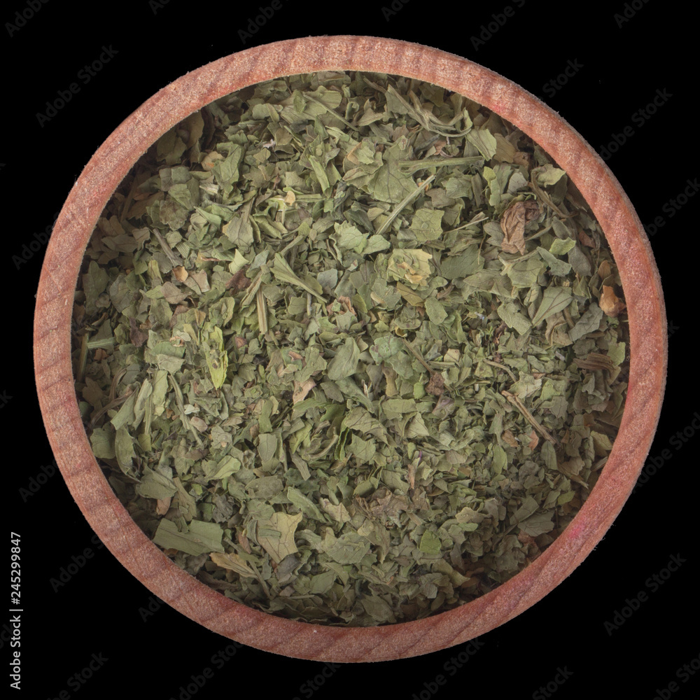 dried ground  mint  in wooden cup isolated on black background. top view