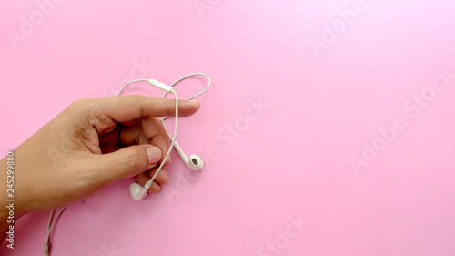 hand hold and earphone on pink background