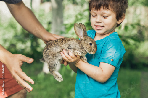 Little boy is holding a bunny at the farm