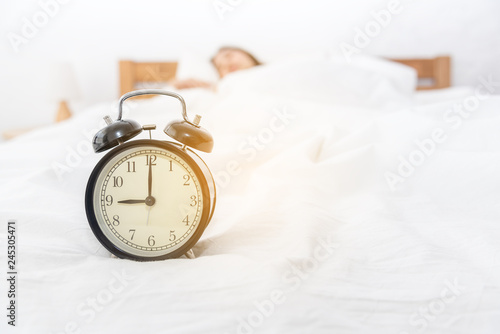 Sleepy asian woman in morning trying to turn off alarm clock in bedroom at home.wake up in morning time.