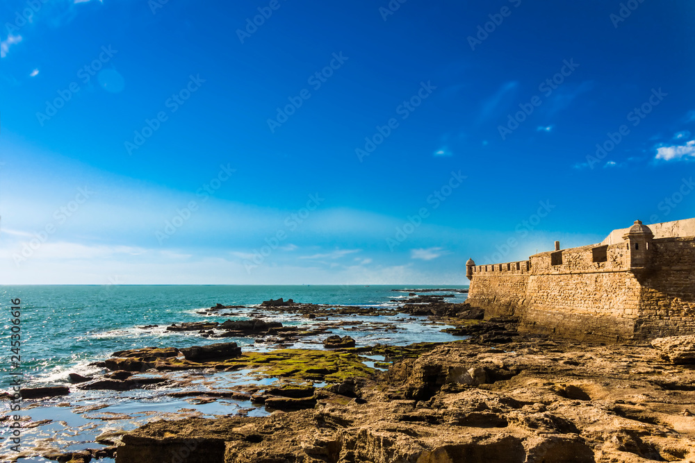 Moss covered rocks off the coastline of Castillo de San Sebastian in Cadiz