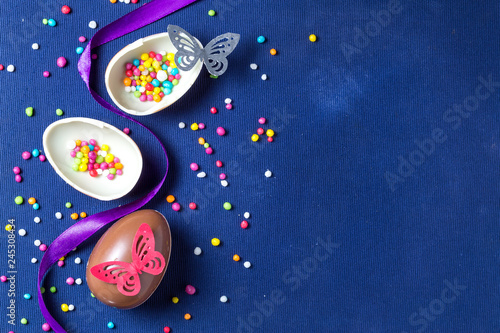 Chocolate Easter eggs with many color sweet over blue background.