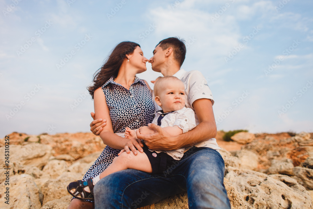 Mom, dad and son. The family strolls along the stony beach by the sea. Mom, dad and son. The family strolls along the stony beach by the sea.