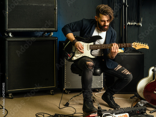 Handsome man playing an electric guitar in a studio photo