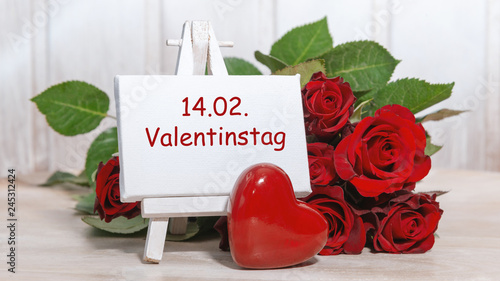 Erinnerung: 14.02. ist Valentinstag, Schild mit roten Rosen vor shabby Holzhintergrund