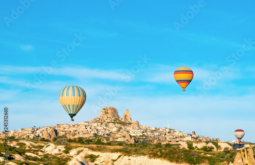 Colorful hot air balloons flying near Uchisar castle at sunrise, Cappadocia, Turkey