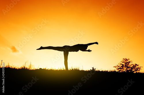 Fototapeta Naklejka Na Ścianę i Meble -  Silhouette of a yogi at sunset. Exercises for the balance.