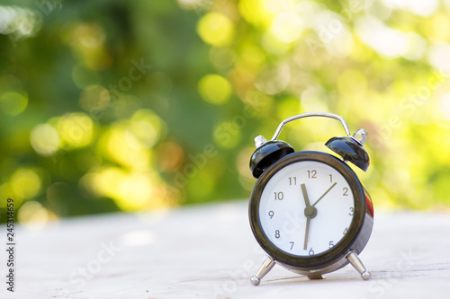 Alarm clock on a light surface on a natural background. Summer concept