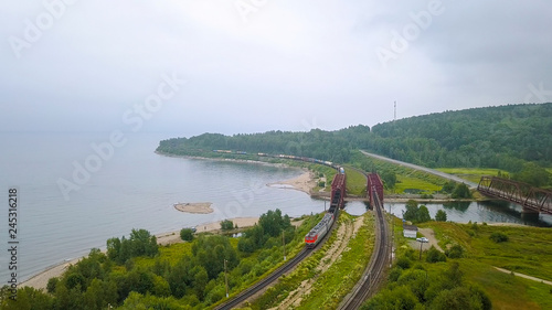 Trans-Siberian Railway, the coast of Lake Baikal. Movement of trains on the iron bridge across the river flowing into Baikal. Russia, From Drone photo