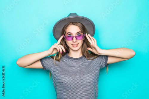 Young woman holding sunglasses and fluppy hat isolated on pastel blue background photo