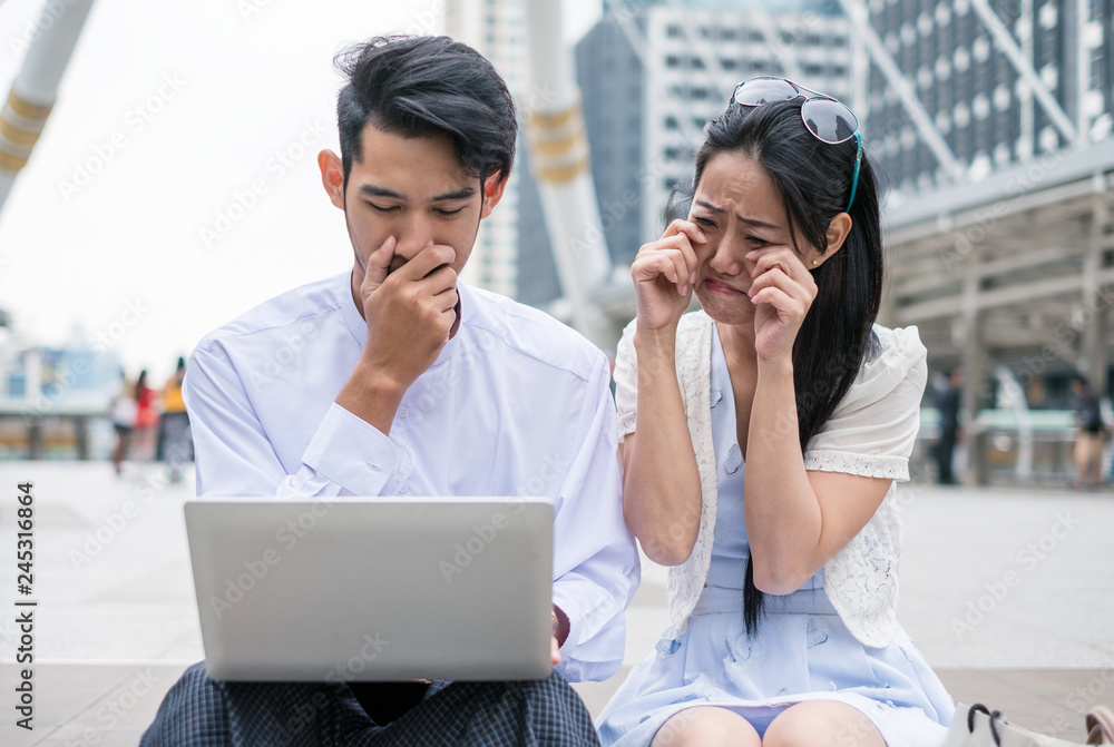 Couples are sit using laptop with sad about incident something in urban Couples are sit using laptop with sad about incident something in urban