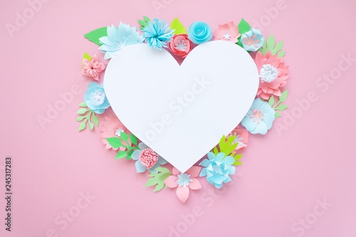Heart frame with paper flowers on pink background. Cut from paper.