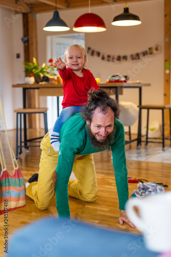 Father playing with adorable infant son at the floor of living room.