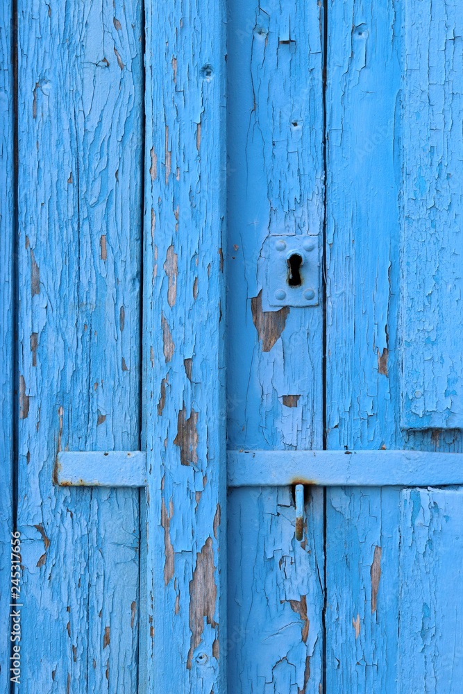 Blue peeling paint on an old wooden barn wall.