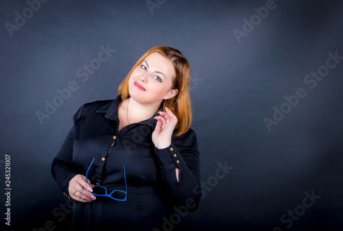 Obraz na plátně Beautiful chubby  girl in a black dress on a dark background
