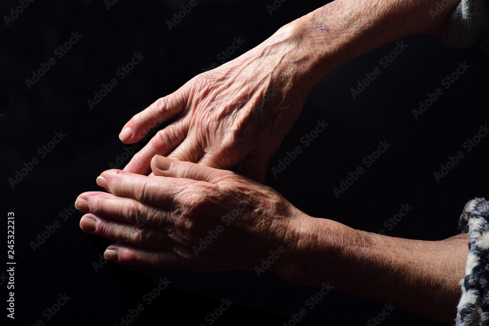 Fototapeta premium hands of senior woman on black