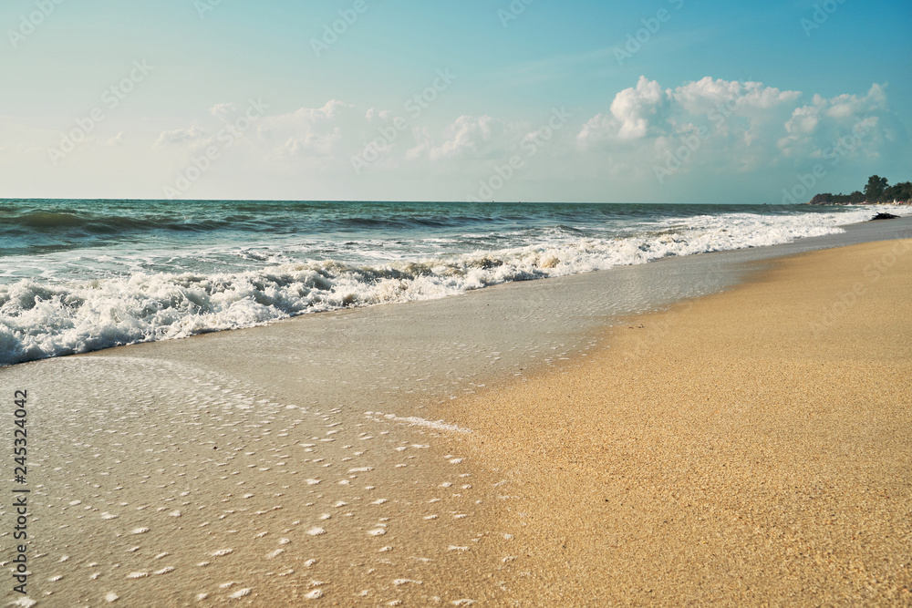 Wild sandy beach with surf. Blue sky in the background