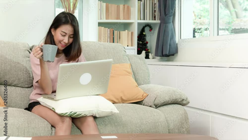 attractive young Asian woman drinking coffee during happy working with notebook computer sitting on sofa in beautigul decoration living room, happy lifestyle, RAW, UHD, 4K, 23.98, Proresss444 attractive young Asian woman drinking coffee during happy working with notebook computer sitting on sofa in beautigul decoration living room, happy lifestyle, RAW, UHD, 4K, 23.98, Proresss444