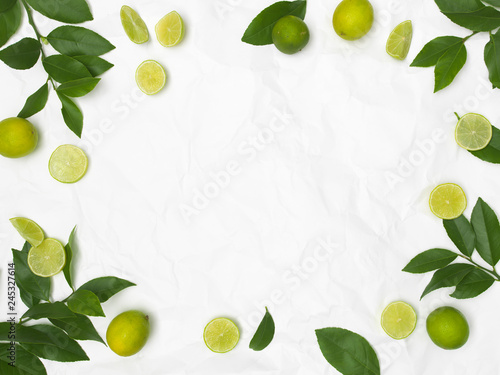 limes and green leaves on white crumpled background