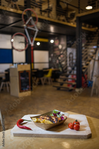 Grilled chicken breast with fries on a wooden board with fresh vegetables