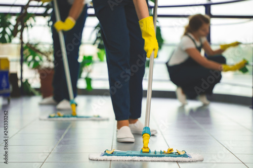 Close-up on person with yellow gloves holding mop while cleaning the floor photo