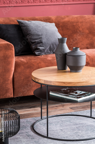 black fancy vases on round wooden coffee table in front of brown velvet settee