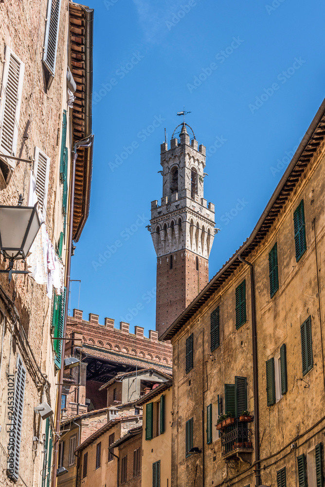 A glimpse of the top of the Torre del Mangia behind Piazza del Campo in Siena
