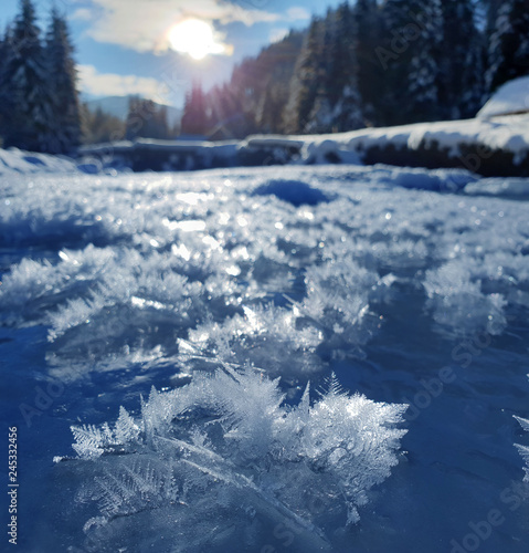 Snowflakes as a snow butterflies over frozen icy river. Frosty nature background.